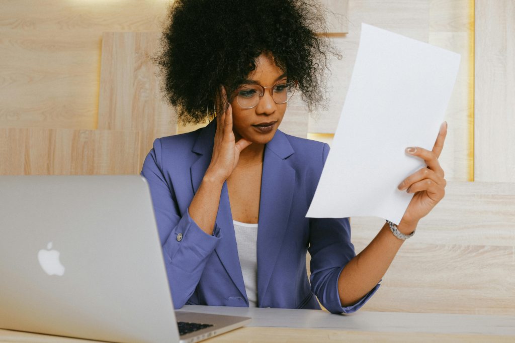 Businesswoman working on a laptop and reviewing a document at the office.